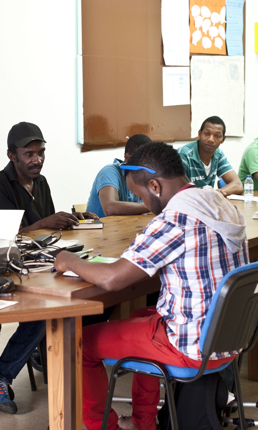 Grupo de participantes numa sessão de formação do Moinho da Juventude, sentados à volta das mesas numa sala